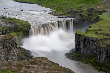 Hafragilsfoss waterfall. Long exposure smooths the glacier river's fierce descent. Stark cliffs frame Iceland's power.