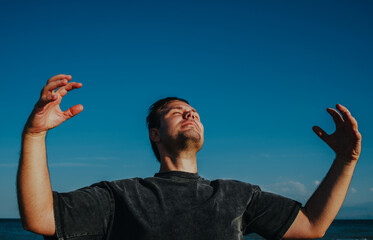 Handsome man enjoying nature portrait on lake shore on blue sky background