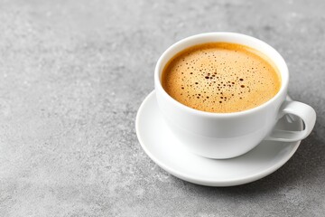 Fototapeta premium Aromatic Coffee Break - A close-up of a steaming cup of coffee on a gray surface. Perfect for breakfast, morning routine, or coffee shop themes