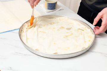 woman in kitchen adding olive oil to spinach pie