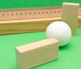 Still life with wooden blocks and a a plastic foam ball on green background