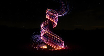 Obraz premium A light painting of a spiral shape with sparks at the base on a dark night with stars above it all