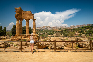A woman exploring the Valley of the Temples (Valle dei Templi), Temple of Castor and Pollux one of the greeks temple of Italy, Agrigento, Sicily. Temple of Concordia, Agrigento, Sicily, Italy. 