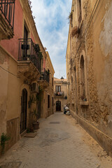 Narrow street in the old town of Syracuse in Sicily, Italy in a beautiful summer day. Travel and sightseeing journey concept