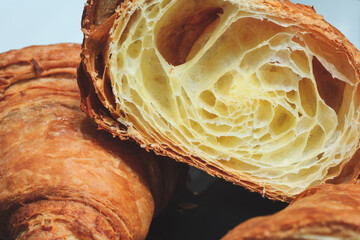A croissant is cut in half, revealing its flaky, buttery layers. Concept of indulgence and luxury,...