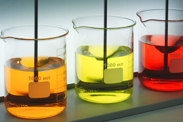 Mixers in the laboratory stir multi-colored liquids in chemical flasks. Analytics medicine pharmaceuticals microbiology concept