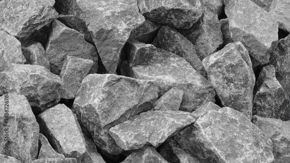 Poster A pile of gray rocks with a rough texture. The rocks are piled up in a way that they form a wall. Concept of ruggedness and strength, as the rocks seem to be unyielding and solid
