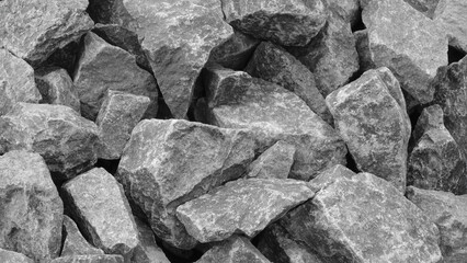 A pile of gray rocks with a rough texture. The rocks are piled up in a way that they form a wall. Concept of ruggedness and strength, as the rocks seem to be unyielding and solid