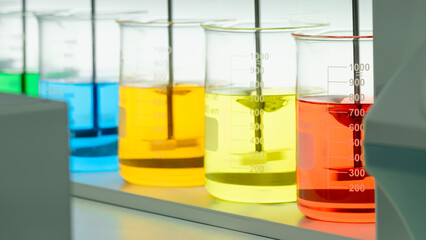 Mixers in the laboratory stir multi-colored liquids in chemical flasks. Analytics medicine pharmaceuticals microbiology concept.