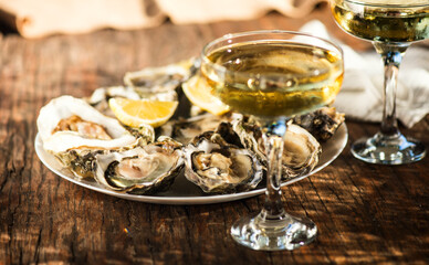 Fresh Oysters with champagne close up, over wood background, open french Fine de Claire oysters. Dinner in a restaurant, sea food. Served table with Oyster. Gourmet food, delicatessen. 