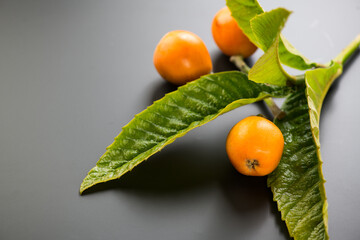 Loquat fruit or Japanese medlars, Nispero, Eriobotrya japonica with leaves fresh ripe bio vegetarian food, medlar berries. Close up. On black background table, top view 