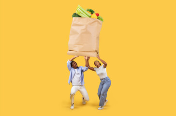 A couple is lifting a large paper grocery bag filled with fresh vegetables and fruits. They are smiling, showcasing the joy of shopping together despite the challenges of today's world.