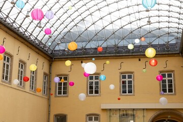 Vibrant courtyard adorned with colorful hanging lanterns under a glass roof creating a whimsical...