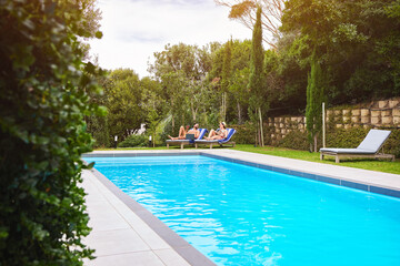 Swimming pool, people and chairs outdoor for relax, travel and summer at luxury hotel as holiday. Water, couple and sun loungers for wellness, hospitality and vacation at resort in Bali with freedom