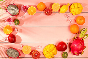 Summer banner with tropical exotic fruits with space for text. Dragon fruit, pitaya, mango, kiwi, avocado, apples, citrus and oranges on sunny table. Healthy vegan food for weight loss