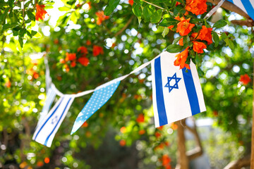 A garland of Israeli flags, among branches of a blooming pomegranate. Israel Independence Day - Yom...