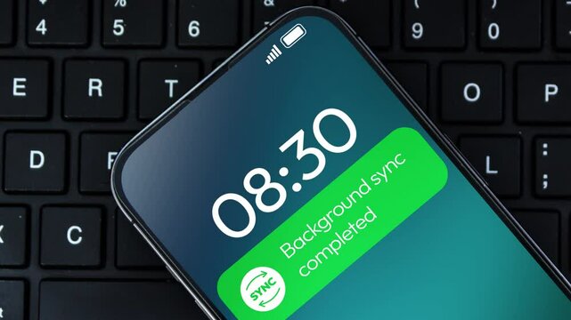 Background synchronization completed notification on the smartphone screen, 4k footage close up. Device sync, data sharing.