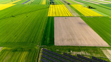 Field of crops with a few black squares in the middle. Aerial view of landscape.