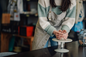 Potter creating clay vessel on pottery wheel in workshop