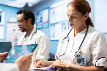 Group of diverse doctors in a treatment center reviewing brain scan results, examining neurology...