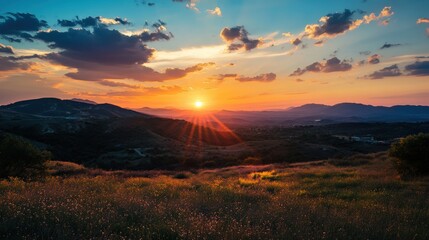 Mountains Field Sun Sky Clouds Orange Horizon Landscape. Bright sun rays over dark hills at sundown. Colorful sky and nature scenic.