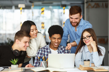 Education concept. University students using laptop in library, preparing for lectures