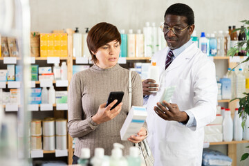 Obraz premium Woman in pharmacy scans QR code atopic cream product, checks certificate on manufacturers website. Client learns information about product, reviews and recommendations for use