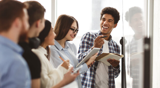 High school friends laughing, solving problems on whiteboard and taking notes