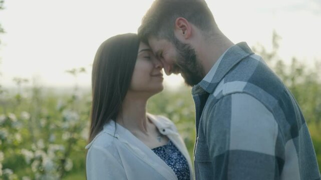 Young couple sharing a romantic moment in a sunlit orchard during a spring afternoon