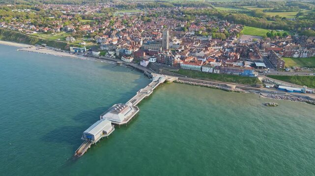 Aerial drone footage of Cromer pier and the coastal town. Turquoise North Sea and the promenade. North Norfolk, England, UK