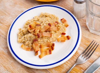 Delicious oatmeal porridge served with fried lard on platter