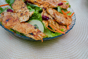 Imagen horizontal de un plato de ensalada con pechuga e pollo y arandanos 