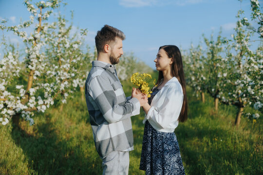 Young couple enjoying a romantic moment in a blooming orchard under a clear sky - Powered by Adobe