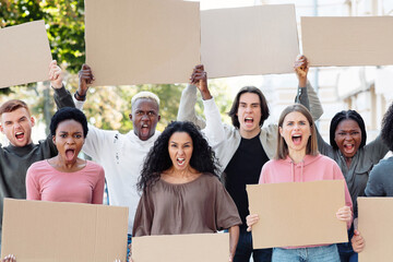 Furious mutiracial group of demonstrators protesting on the street, holding blank placards....