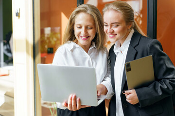 Two professionals engage in lively collaboration while reviewing a presentation on a laptop in a...