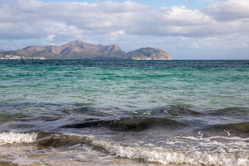 Mediterranean beach on the island of Majorca, or Mallorca on Balearic Sea, are part of Spain. Island in the Mediterranean Sea. Seaside vacations, clouds, seascape. View of the sea and the island.  
