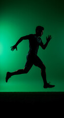 Obraz premium Silhouette of a Runner in Action with Green Background and Dynamic Pose