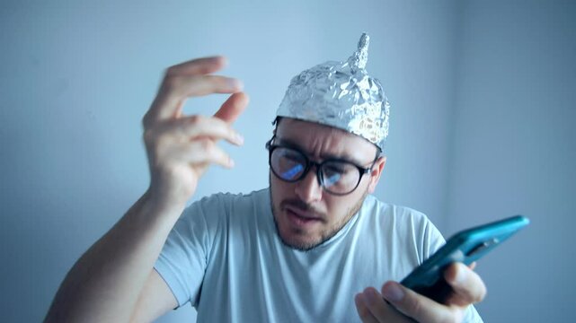 Man wears aluminum foil hat while expressing disbelief and paranoia in a humorous portrayal of conspiracy theories
