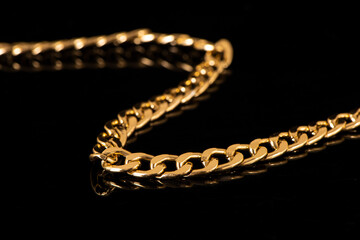 closeup of gold jewelry chains set on black background. 