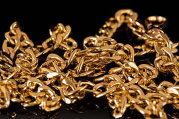 closeup of gold jewelry chains set on black background. 