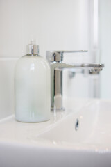 Bathroom, soap and dispenser at hotel for accommodation with cleaning equipment at resort. Closeup of interior, sink tap or faucet with container, bottle or domestic decor of toiletries at home