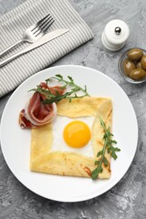 Delicious crepe bretonne with bacon and arugula served on grey textured table, flat lay
