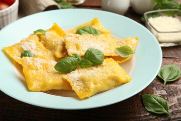 Delicious ravioli with cheese and basil on wooden table, closeup