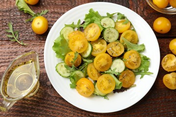 Fresh salad with yellow tomatoes on wooden table, flat lay