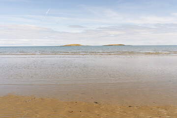 The beach is calm and peaceful with a clear blue sky in the background