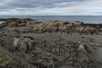 A rocky shoreline with a cloudy sky in the background