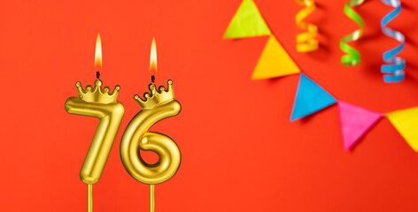 Number 76 birthday candle on an orange background with pennants