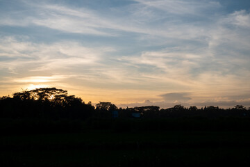 Blue background of sky and clouds in the evening with a panoramic view of the sunset and shadows from the trees