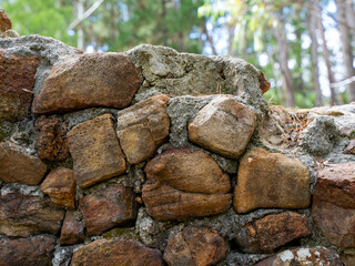 Old stone wall in forest clearing with green trees and grass