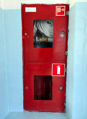 red cabinets house fire hoses and extinguishers in well-maintained facility. clear signage ensures immediate access for emergencies, promoting safety and preparedness.